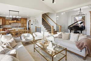 Living area with a chandelier, recessed lighting, lofted ceiling, and stairway