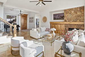 Living room featuring a fireplace, stairway, stone tile floors, ceiling fan, and lofted ceiling