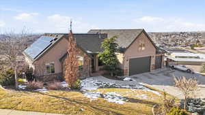 View of front of property with stucco siding, stone siding, driveway, and roof mounted solar panels