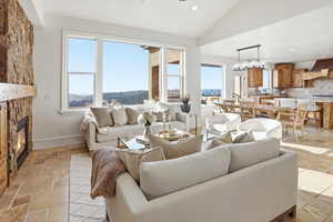 Living room with stone tile floors, recessed lighting, lofted ceiling, and a stone fireplace