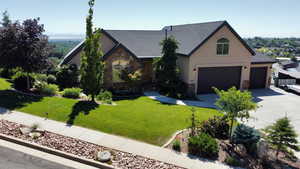 View of front of property with stone siding, stucco siding, driveway, and a front yard