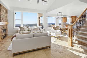 Living room with lofted ceiling, stairway, recessed lighting, a stone fireplace, and ceiling fan