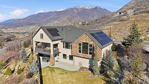 Back of house featuring a patio, a mountain view, stucco siding, solar panels, and a shingled roof