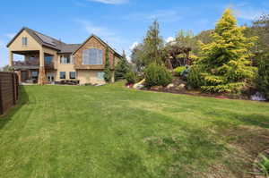 Back of property with a lawn, stucco siding, and a balcony