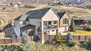 Rear view of house with a balcony, stucco siding, and a fenced backyard