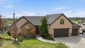 View of front of property with stone siding, stucco siding, a front yard, concrete driveway, and a shingled roof