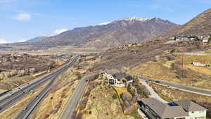 Aerial view of property and surrounding area featuring mountains and a highway