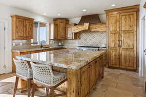 Kitchen with brown cabinets, a center island, tasteful backsplash, a kitchen bar, and recessed lighting