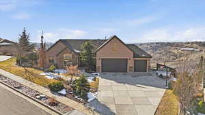 View of front facade featuring stone siding, a shingled roof, concrete driveway, and stucco siding
