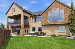 Back of property with a patio, outdoor seating, stucco siding, solar panels, and a hot tub