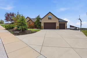 View of front of home featuring stucco siding, stone siding, driveway, and an attached garage