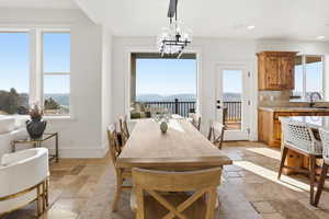 Dining room with plenty of natural light, stone tile flooring, a water and mountain view, a chandelier, and recessed lighting