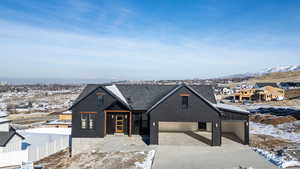 Modern farmhouse featuring a mountain view, driveway, brick siding, and a garage