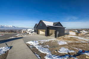 View of snow covered exterior featuring a garage, driveway, and a mountain view