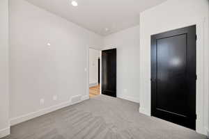 Unfurnished bedroom featuring light colored carpet and baseboards
