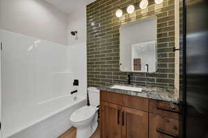 Full bath with tile walls, vanity, washtub / shower combination, and tasteful backsplash