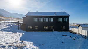 Snow covered back of property featuring a deck with mountain view