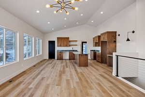 Kitchen with a chandelier, open shelves, a kitchen island, light wood finished floors, and brown cabinets