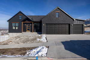 View of front facade with brick siding, driveway, and board and batten siding