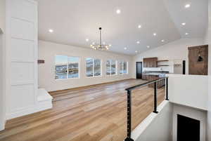 Kitchen with open shelves, a chandelier, lofted ceiling, recessed lighting, and light wood-type flooring
