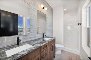 Bathroom featuring double vanity, backsplash, a marble finish shower, recessed lighting, and healthy amount of natural light