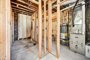 Unfinished below grade area featuring water heater and heating unit