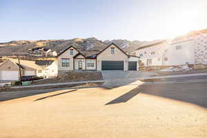 View of front of house with a mountain view, driveway, and stone siding