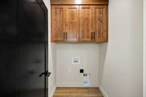 Laundry room with light wood-type flooring, cabinet space, and washer hookup
