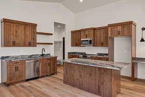 Kitchen featuring open shelves, dark stone countertops, wood finish cabinetry, stainless steel appliances, and light wood-type flooring