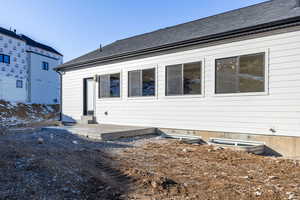 Rear view of property featuring roof with shingles and entry steps