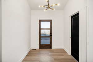 Entryway featuring light wood-type flooring and suspended lighting