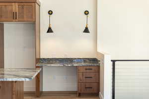 Kitchen featuring wood finish cabinets, light wood finished floors, light stone countertops, and pendant lighting