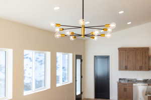 Kitchen with wood finish cabinetry, stainless steel dishwasher, dark stone countertops, and a chandelier