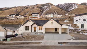 View of front facade with driveway, a mountain view, a porch, stone siding, and a residential view