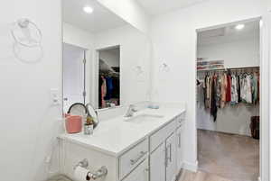Bathroom featuring a walk in closet, vanity, recessed lighting, and light wood-style flooring