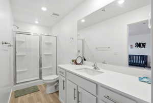 Full bath featuring light wood-style floors, vanity, a shower stall, and recessed lighting