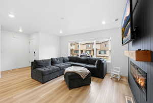 Living area featuring a glass covered fireplace, light wood finished floors, and recessed lighting