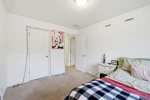 Bedroom with light colored carpet and a textured ceiling
