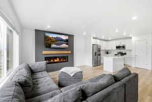 Living area featuring light wood-style floors, a large fireplace, and recessed lighting