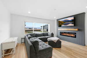 Living room featuring light wood finished floors, a fireplace, and recessed lighting