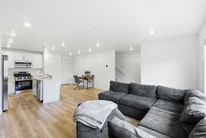 Living area featuring recessed lighting, light wood-style flooring, a desk, and stairs