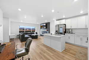 Office area featuring light wood-style floors, recessed lighting, and a glass covered fireplace