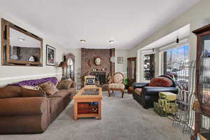 Formal living room featuring carpet floors, a brick fireplace, and a textured ceiling