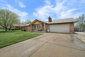 Ranch-style home featuring concrete driveway, brick siding, a chimney, and a garage