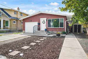 View of front of property with concrete driveway, brick siding, a garage, and a storage unit