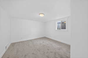 Spare room featuring light colored carpet and baseboards