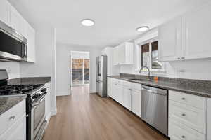Kitchen featuring appliances with stainless steel finishes, white cabinetry, and dark stone counters