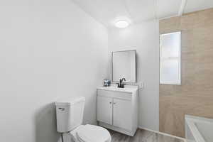 Bathroom with vanity, a bath, and wood finished floors