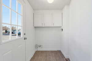 Laundry area featuring hookup for a washing machine, cabinet space, and light wood finished floors