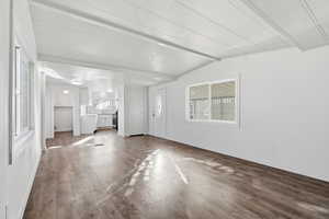 Unfurnished living room with beam ceiling and dark wood-style floors